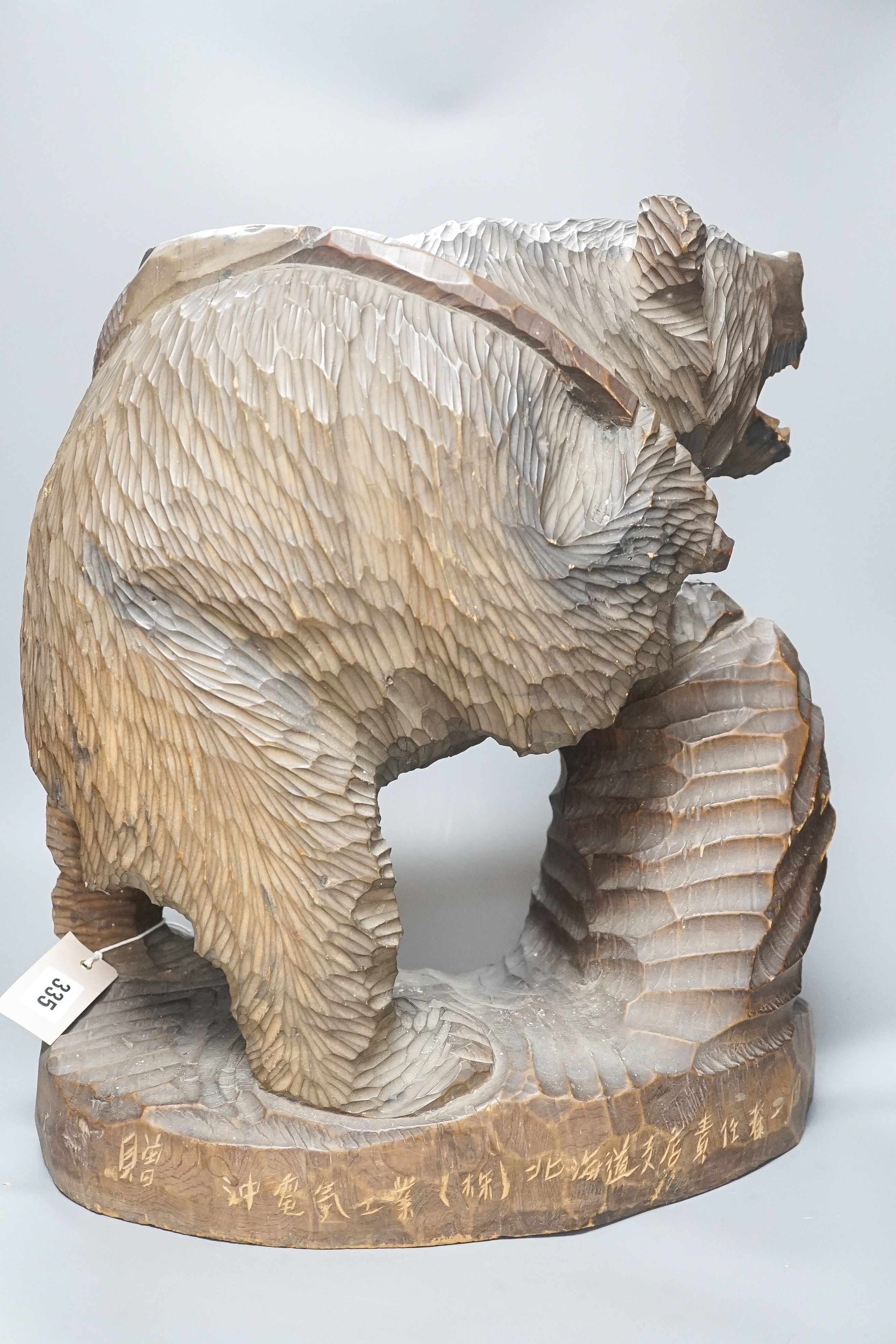 A large Japanese carved wooden bear holding a fish, inscribed 47cm